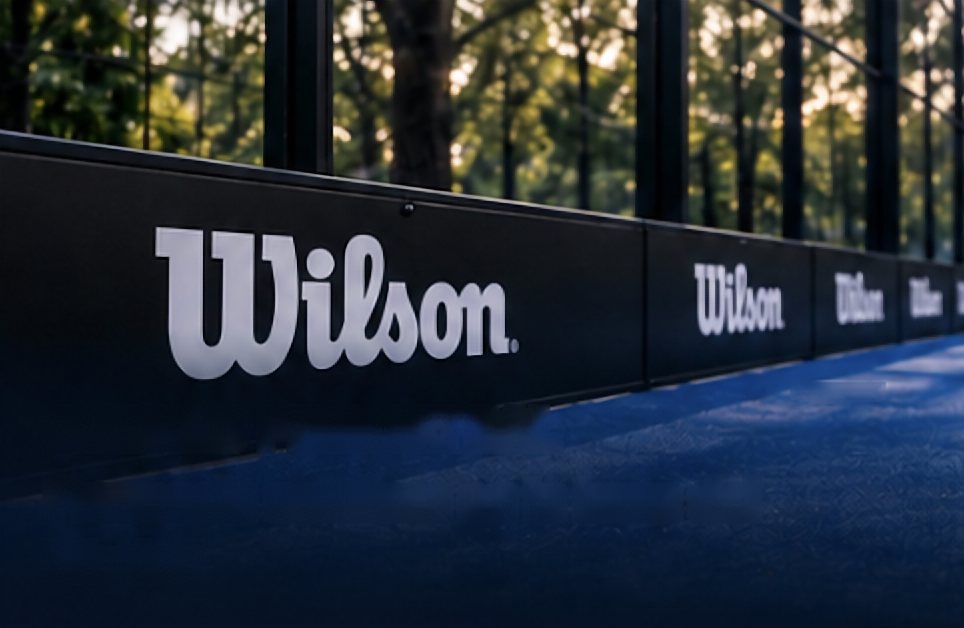 Zócalo perimetral con la marca Wilson en la base del cristal de una pista de pádel